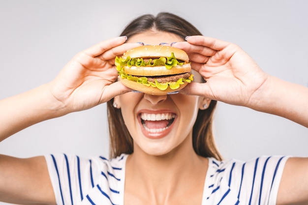 Junge glückliche schöne Frau, die Hamburger isst