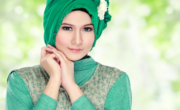 Junge glückliche schöne muslimische Frau mit grünem Kostüm, das Hijab trägt
