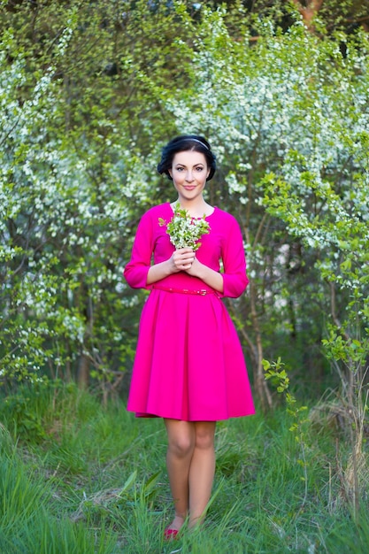 junge glückliche schöne verträumte frau im rosa kleid, das im frühjahr kirschgarten geht