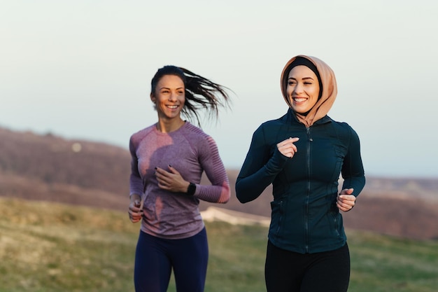 Junge glückliche Sportlerinnen joggen mit Personal Training in der Natur
