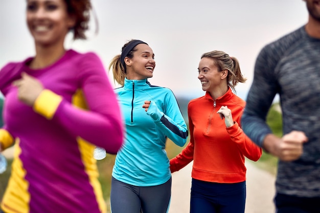 Junge glückliche sportliche Frauen kommunizieren beim Laufen von Marathon in der Natur