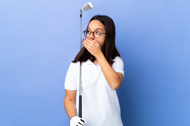 Junge Golferfrau über isolierte bunte, die Überraschungsgeste tut, während sie zur Seite schaut