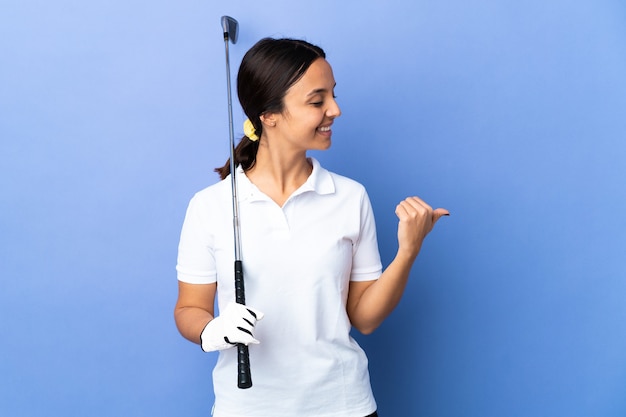Junge Golferfrau über lokalisiertem buntem Hintergrund, der zur Seite zeigt, um ein Produkt zu präsentieren