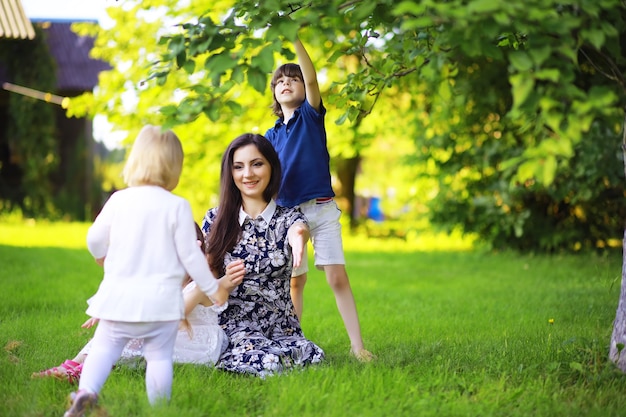 Junge große Familie auf einem Sommermorgenspaziergang. Schöne Mutter mit Kindern spielt im Park.