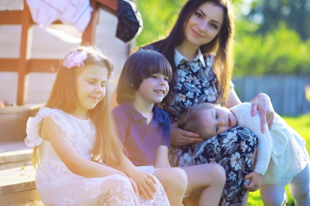 Junge große Familie auf einem Sommermorgenspaziergang. Schöne Mutter mit Kindern spielt im Park.