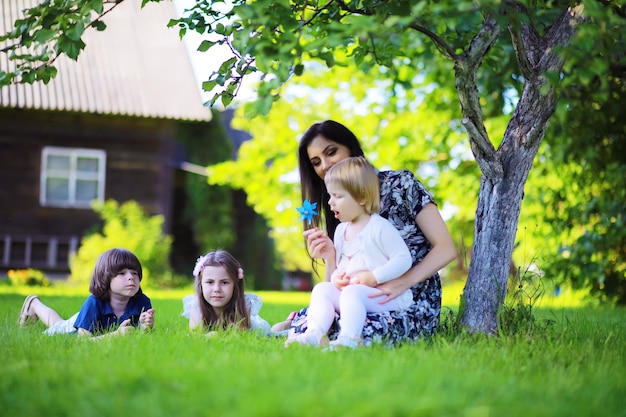 Junge große Familie auf einem Sommermorgenspaziergang Schöne Mutter mit Kindern spielt im Park