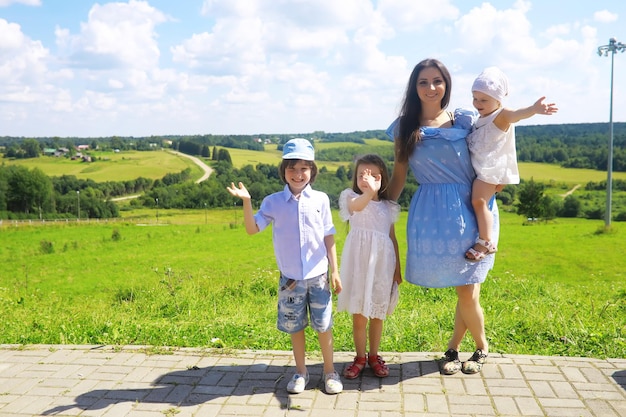 Junge große Familie auf einem Sommermorgenspaziergang Schöne Mutter mit Kindern spielt im Park