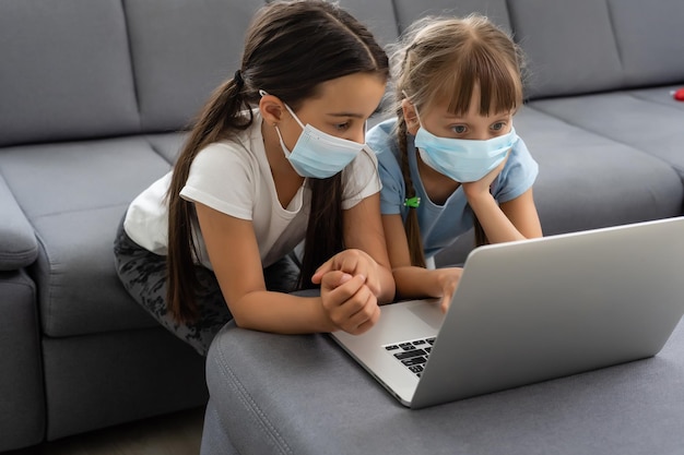 Junge Grundschulmädchen mit Gesichtsschutzmaske beim Online-Bildungsunterricht. Coronavirus- oder Covid-19-Lockdown-Bildungskonzept.