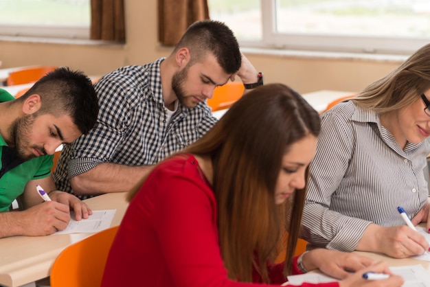 Junge Gruppe attraktiver Teenager-Studenten in einem College-Klassenzimmer, die an einem Tisch sitzen und Lektionen lernen