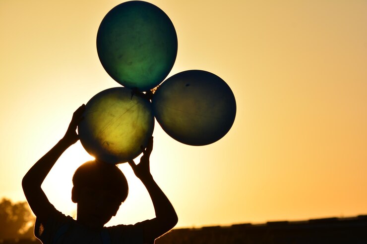 Foto junge hält bei sonnenuntergang ballons gegen den himmel