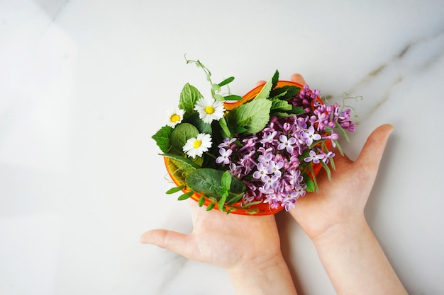 Junge hält eine Komposition von Blumen in Form eines Herzens