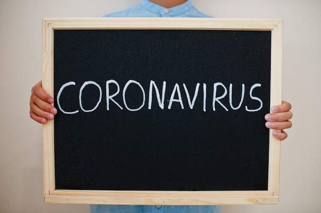 Junge hält Inschrift mit Coronavirus auf der Tafel