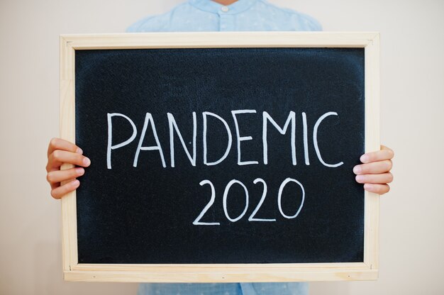 Junge halten Inschrift an der Tafel mit dem Text Pandemic 2020