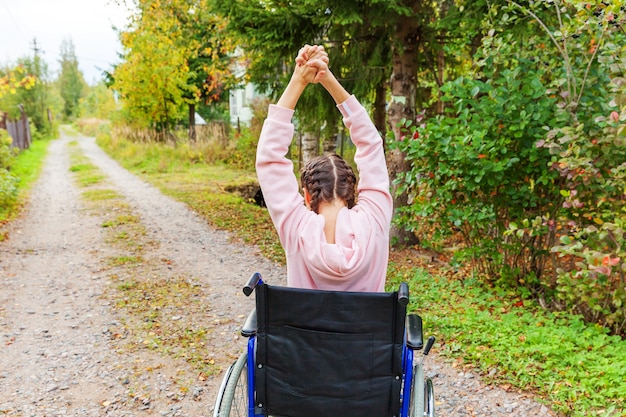 Foto junge handicapfrau im rollstuhl auf straße im krankenhauspark