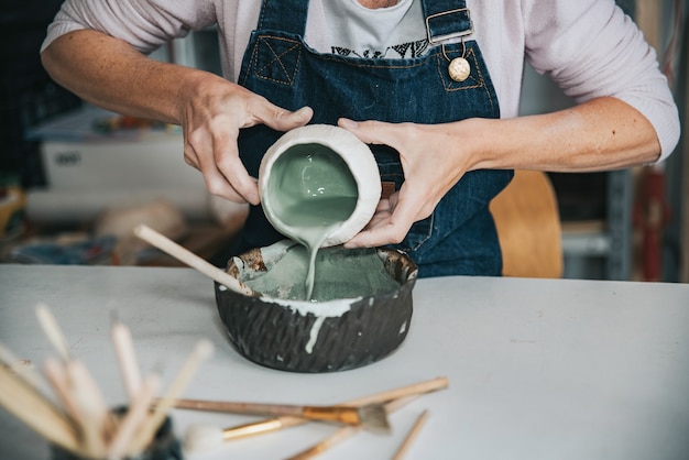 Junge Handwerkerin, die mit ihrer Hand ein Stück Keramikfokus auf Hand arbeitet