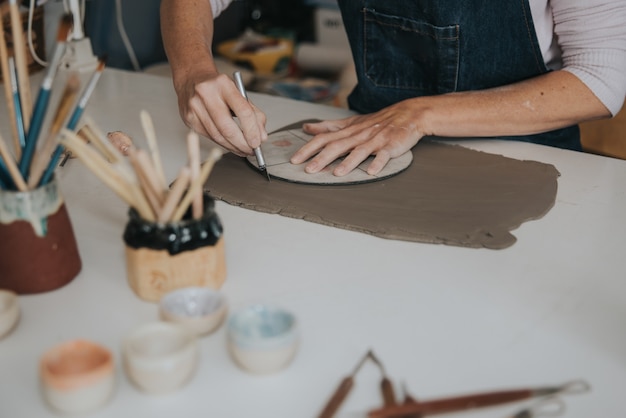 Foto junge handwerkerin, die mit ihrer hand ein stück keramikfokus auf hand arbeitet