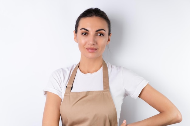 Junge Hausfrau in einer Schürze auf weißem Hintergrund mit einem glücklichen Lächeln auf ihrem Gesicht süß positiv