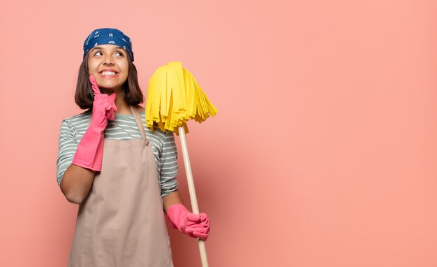 Foto junge haushälterin lächelt glücklich und träumt oder zweifelt und schaut zur seite