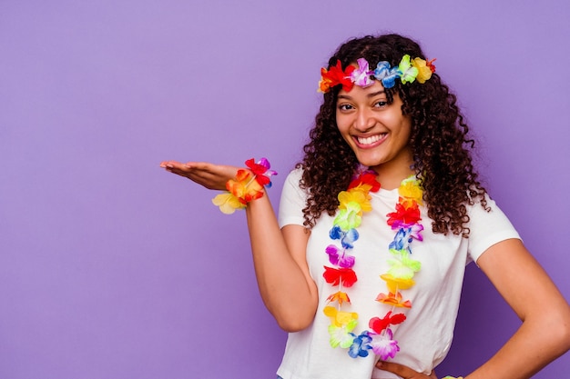 Junge hawaiianische Frau isoliert auf lila Hintergrund, die einen Kopienraum auf einer Handfläche zeigt und eine andere Hand an der Taille hält.