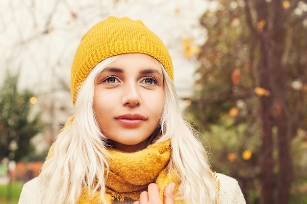 Junge Herbstfrau, die gelben Hut und Schal auf Fall-Natur-Hintergrund trägt. Schönes Mädchen im Freien