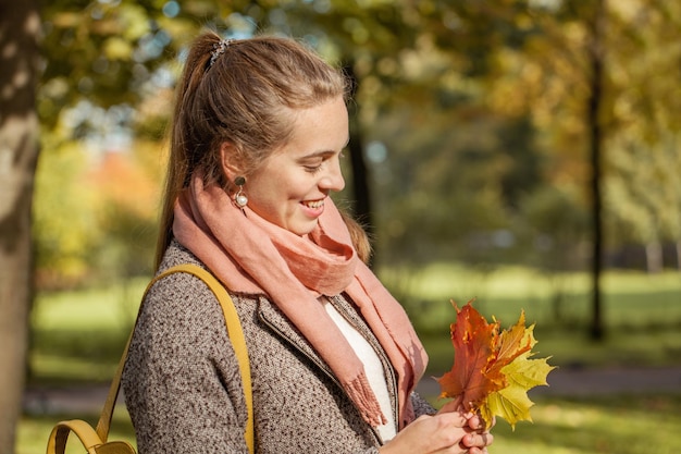 Junge Herbstfrau mit rotem und gelbem Ahornblatt im Freien R