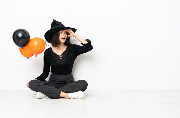 Junge Hexe, die schwarze und orange Luftballons hält