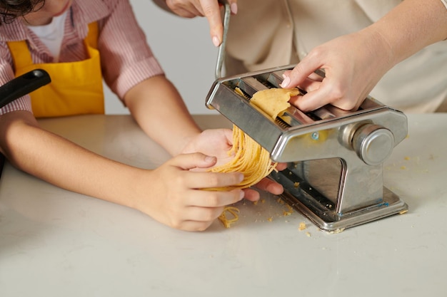 Junge hilft Mutter bei der Herstellung von Spaghetti