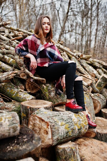 Junge Hippie-Mädchenabnutzung auf Decke gegen hölzerne Stümpfe auf Holz.