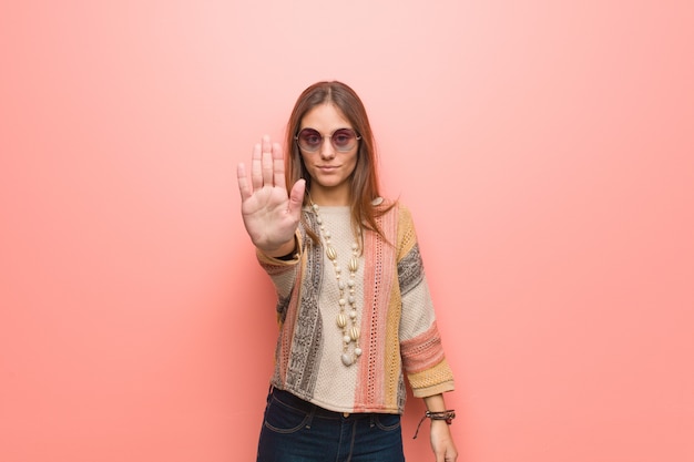 Junge Hippiefrau auf dem Rosa, das Hand in Front einsetzt