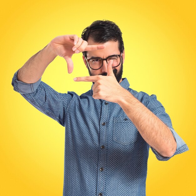 Junge hipster Mann konzentriert sich mit seinen Fingern auf bunten Hintergrund