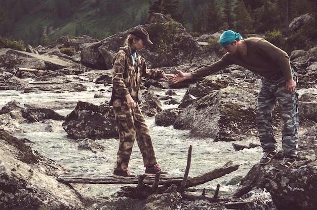 Junge Hipster schöne verliebte Paar zu Fuß auf einem Felsen am Fluss im Wald