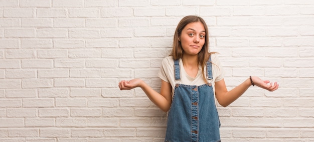 Junge Hipsterfrau zweifelt und zuckt mit den Schultern