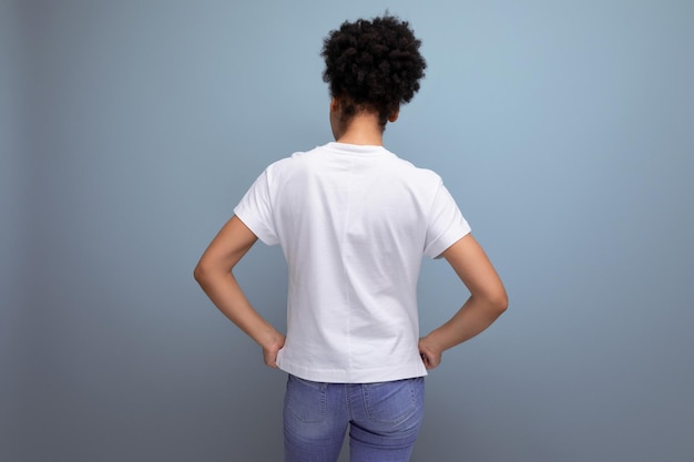 Junge hispanische brünette Frau trägt ein weißes T-Shirt und steht mit dem Rücken da