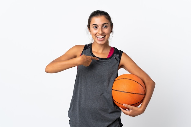 Junge hispanische Frau, die Basketball über isolierte weiße Wand mit überraschendem Gesichtsausdruck spielt