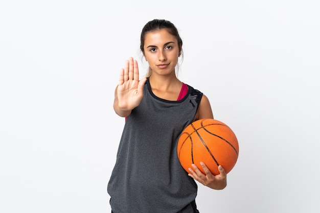 Junge hispanische Frau, die Basketball über lokalisiertem weißem Hintergrund spielt, der Stoppgeste macht