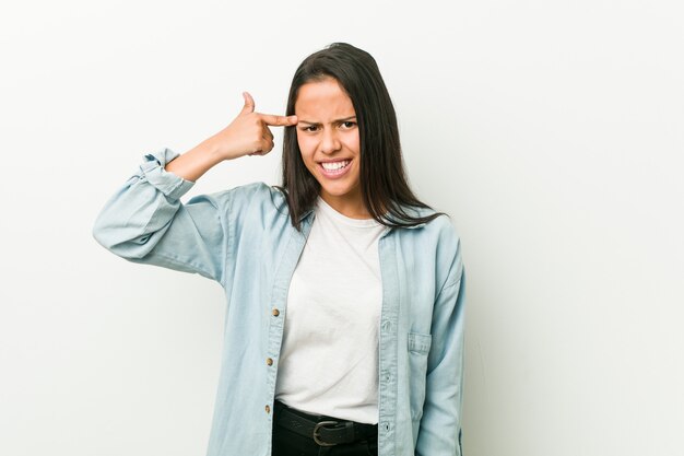 Junge hispanische Frau, die eine Enttäuschungsgeste mit Zeigefinger zeigt.