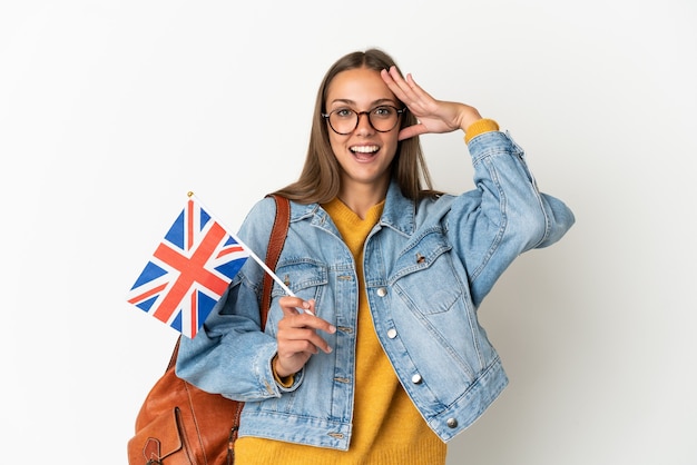 Junge hispanische Frau, die eine Flagge des Vereinigten Königreichs über isoliertem weißem Hintergrund mit Überraschungsausdruck hält