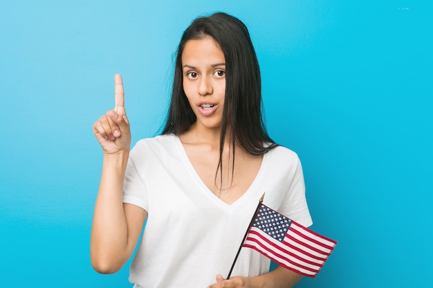 Junge hispanische Frau, die eine Flagge Vereinigter Staaten hat irgendeine großartige Idee hält