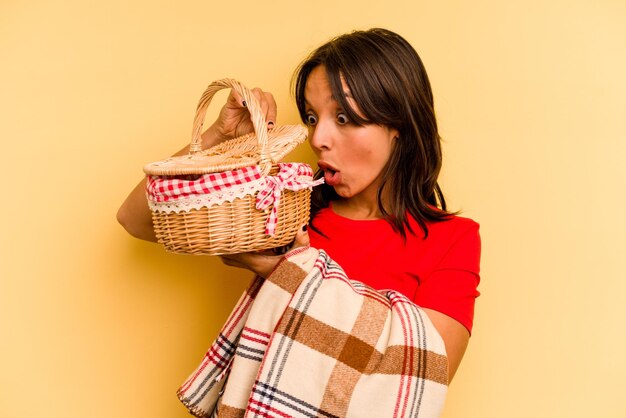 Junge hispanische Frau, die es Picknick machen wird, isoliert auf gelbem Hintergrund