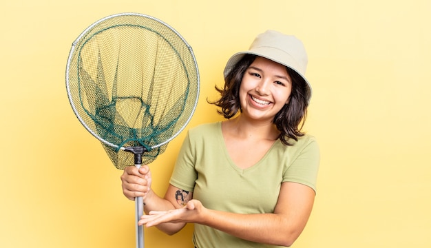 Junge hispanische Frau, die fröhlich lächelt, sich glücklich fühlt und ein Konzept zeigt. Fischernetzkonzept