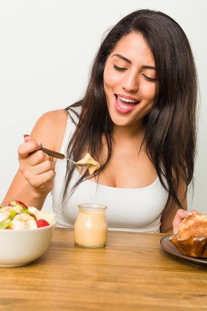 Junge hispanische Frau, die Frühstück auf dem Tisch hat