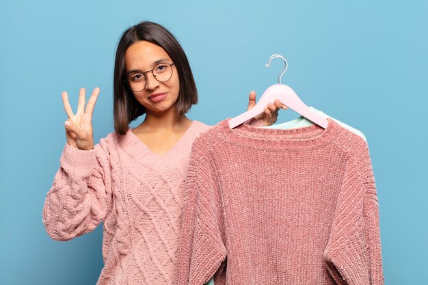 Foto junge hispanische frau, die lächelt und freundlich aussieht, nummer drei oder dritte mit der hand nach vorne zeigend, countdown