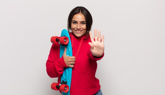 Junge hispanische Frau, die lächelt und freundlich aussieht, Nummer vier oder vierten mit der Hand nach vorne zeigend, Countdown