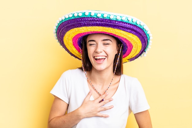 Junge hispanische Frau, die laut über einen urkomischen Witz lacht. mexikanisches Hutkonzept