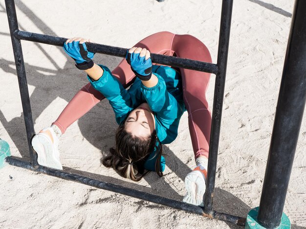 Junge hispanische Frau, die schwierige Flexibilitätsübungen am Spalier macht