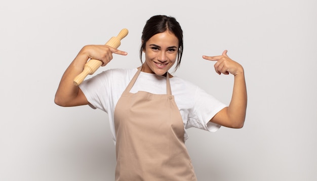 Junge hispanische Frau, die selbstbewusst auf ihr eigenes breites Lächeln lächelt, positive, entspannte, zufriedene Haltung