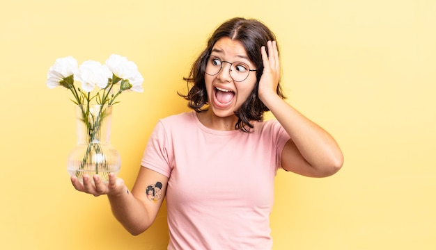 Junge hispanische Frau, die sich glücklich, aufgeregt und überrascht fühlt. Blumentopfkonzept