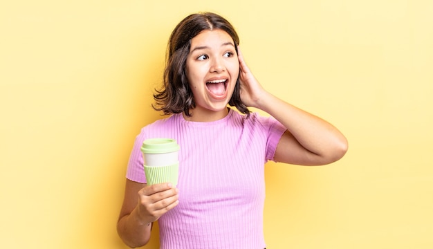 Junge hispanische Frau, die sich glücklich, aufgeregt und überrascht fühlt. Kaffee zum Mitnehmen Konzept