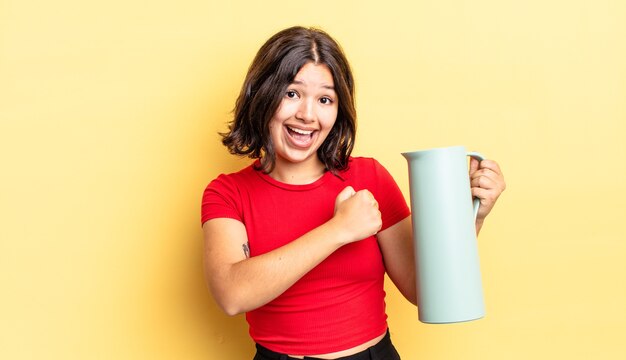 Junge hispanische Frau, die sich glücklich fühlt und einer Herausforderung gegenübersteht oder feiert. Thermos-Konzept