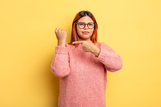 Junge hispanische Frau, die ungeduldig und wütend aussieht, auf die Uhr zeigt, um Pünktlichkeit bittet, will pünktlich sein